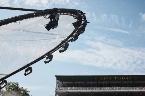 Große Filmscheinwerfer sind auf einem kreisförmigen Gestell über einem Veranstaltungsort im Freien montiert; darunter ist eine Gebäudefassade mit der Aufschrift LIVE TODAY zu sehen.