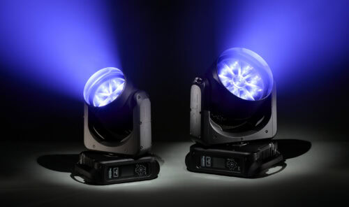 Zwei schwarze Bühnenscheinwerfer strahlen in dunkler Umgebung blaue Lichtstrahlen nach oben ab. Beide Scheinwerfer sind nebeneinander auf schwarzen Sockeln angebracht.