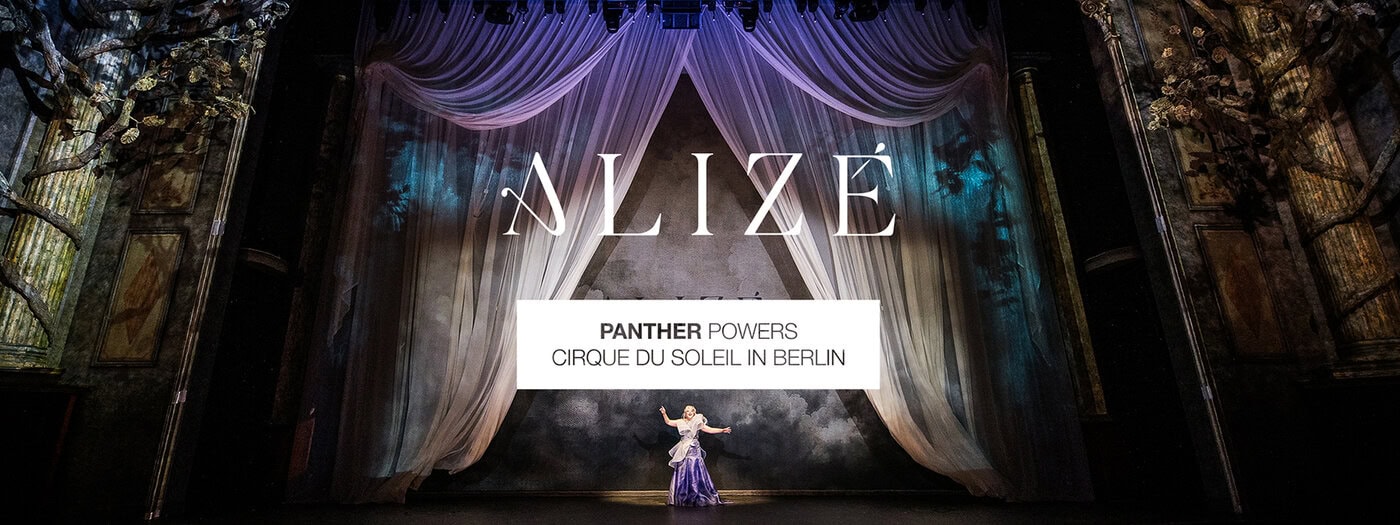 Eine große Bühne mit verschnörkelten Vorhängen und dem Wort ANLIZÉ darüber. Ein Darsteller steht in der Mitte der Bühne. Der Text darunter lautet PANTHER POWERS CIRQUE DU SOLEIL IN BERLIN.