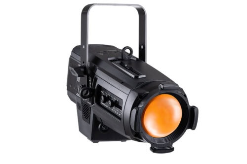 Ein schwarzer Bühnenscheinwerfer mit einer orangefarbenen Linse steht auf einem weißen Hintergrund. Die Leuchte hat Einstellknöpfe und einen Tragegriff aus Metall an der Oberseite.